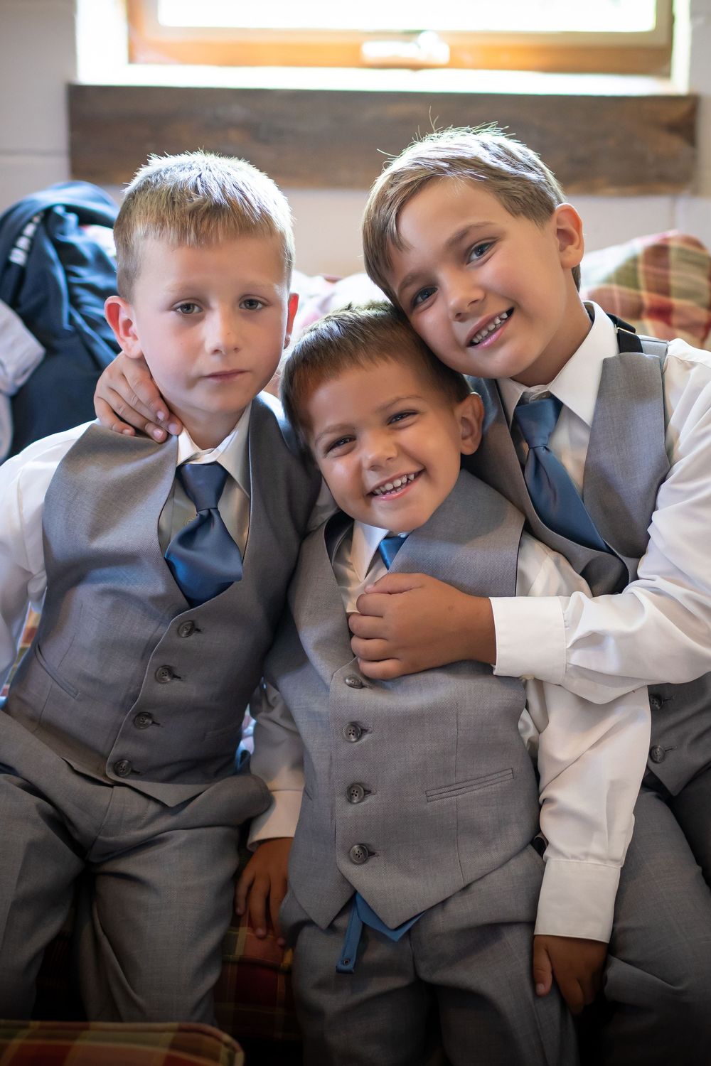 Young groomsmen in matching gray vests and white shirts pose playfully together.