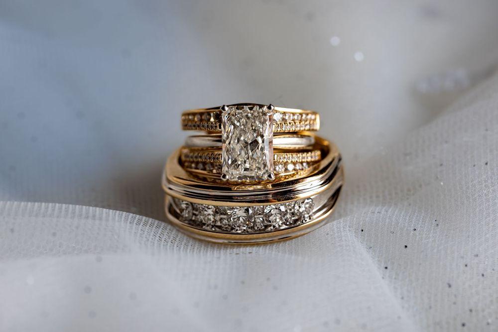 Close-up photos of elegant gold and diamond wedding rings on white fabric.