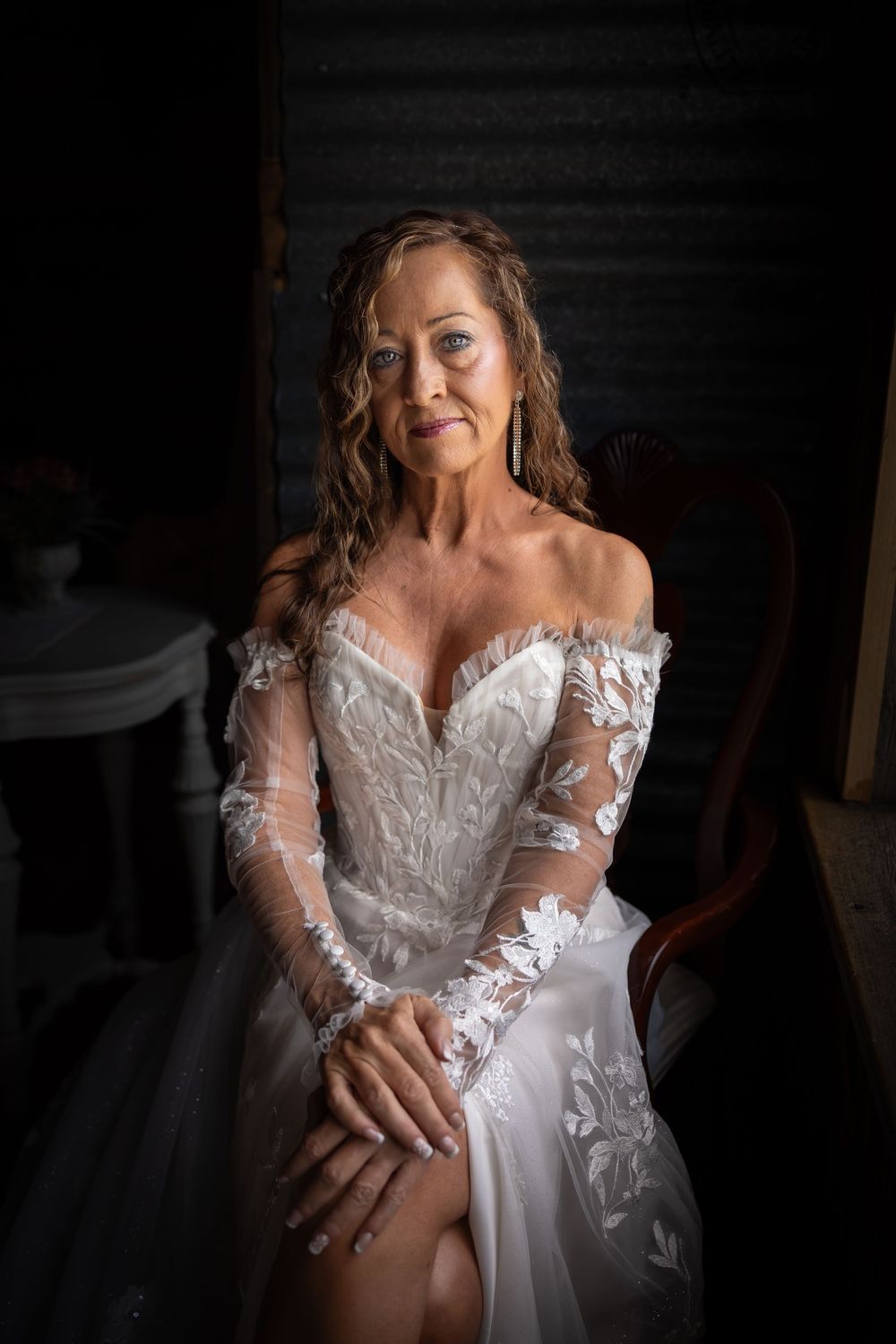 Bride in an elegant off-shoulder lace wedding gown poses for a portrait.