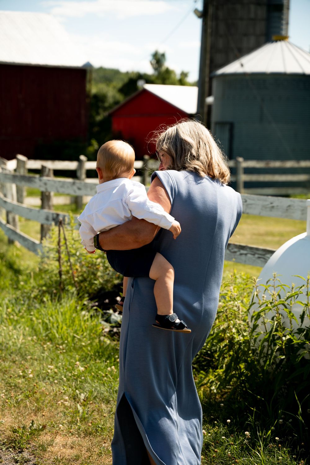 A series of candid outdoor photos showing people walking through a sunny field near farm buildings.