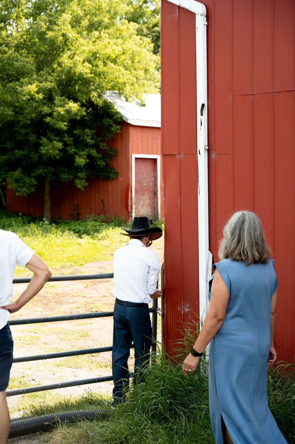 People peeking behind a red barn wall in sequence, creating a playful disappearing effect.