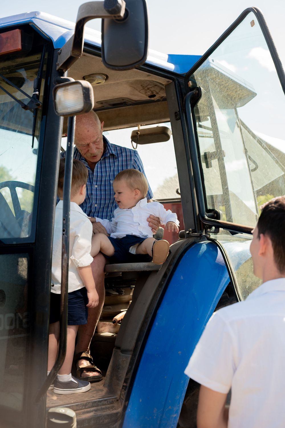 Family members gather inside a blue tractor cab for a special moment together.