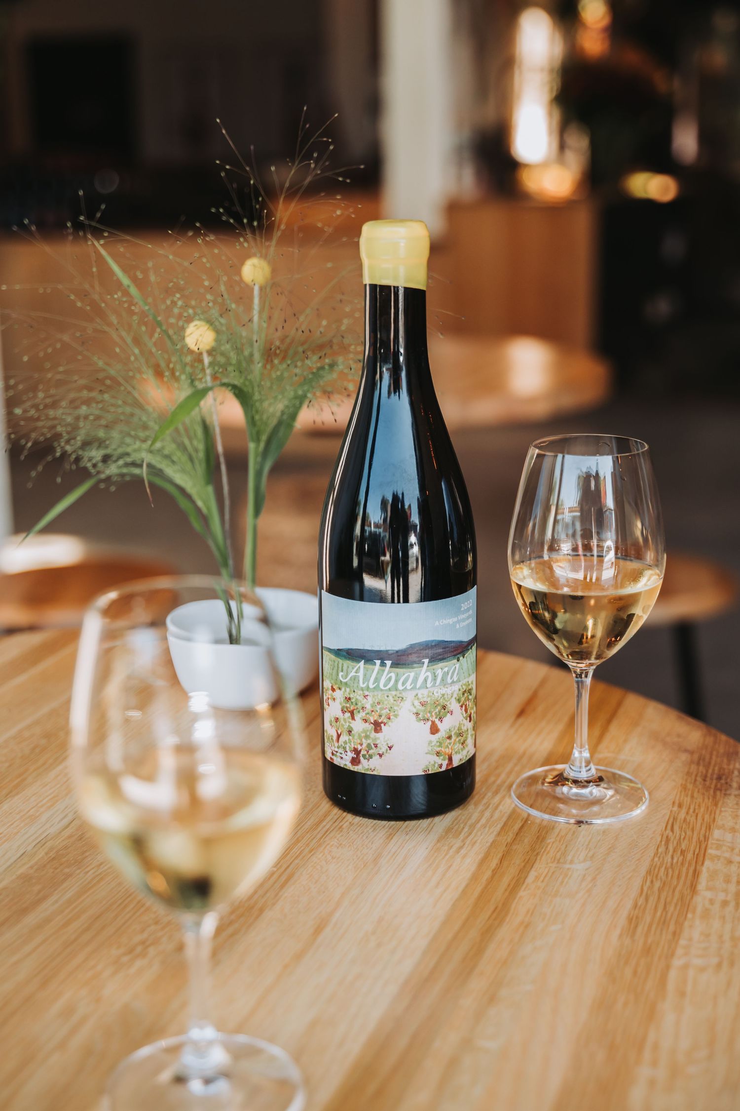 Four wine tasting photos show hands holding glasses and bottles at a wooden table in a cozy restaurant setting.