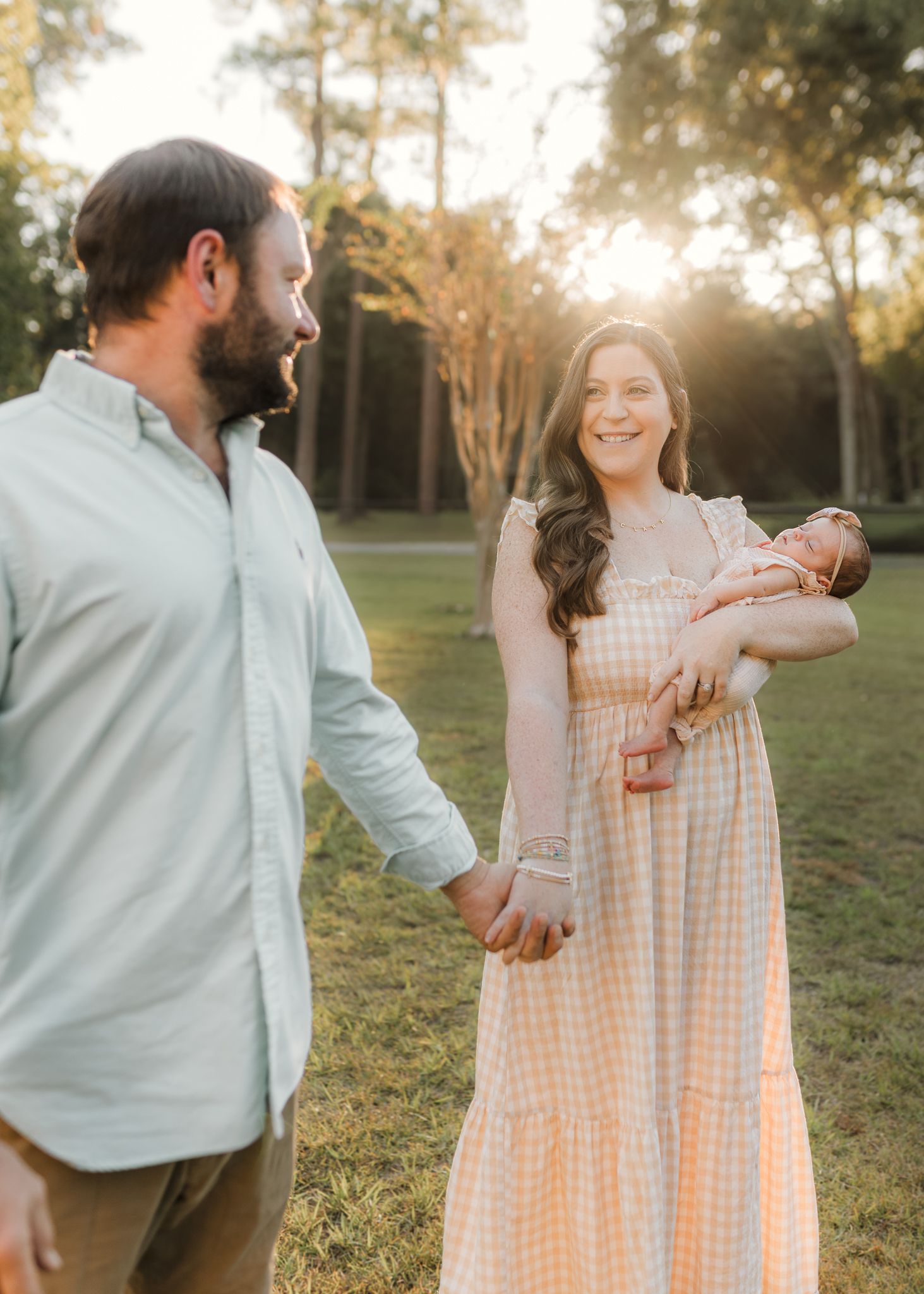 A couple shares tender moments in a sunlit outdoor setting wearing light colored clothing at golden hour.