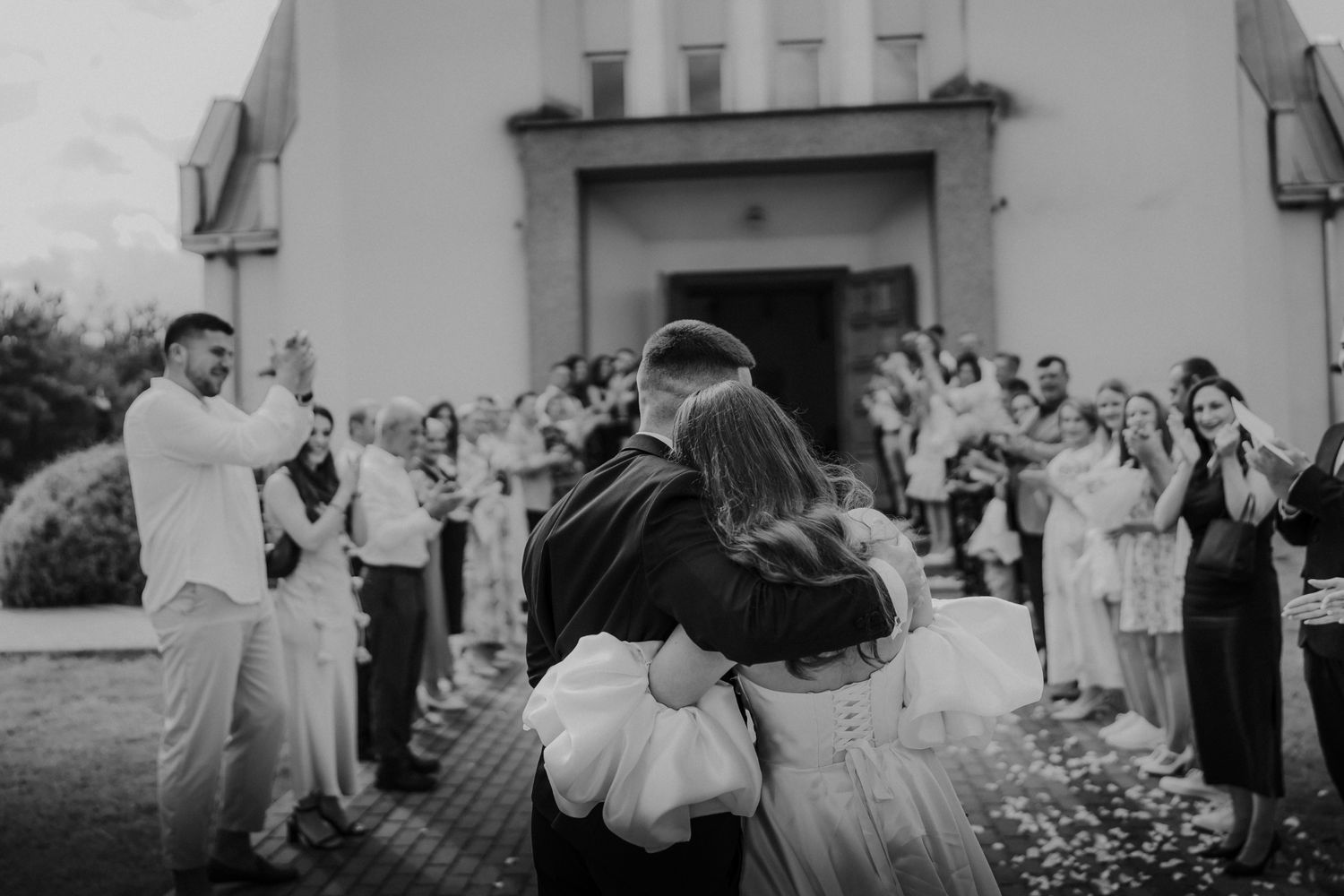Wedding guests celebrating outside church entrance with confetti.