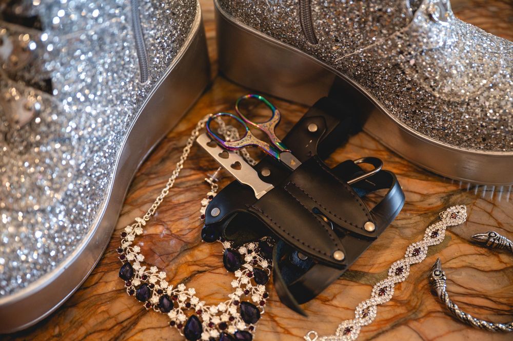 A close-up view of wedding jewelry and accessories arranged on a wooden surface with sparkly decor in the background.