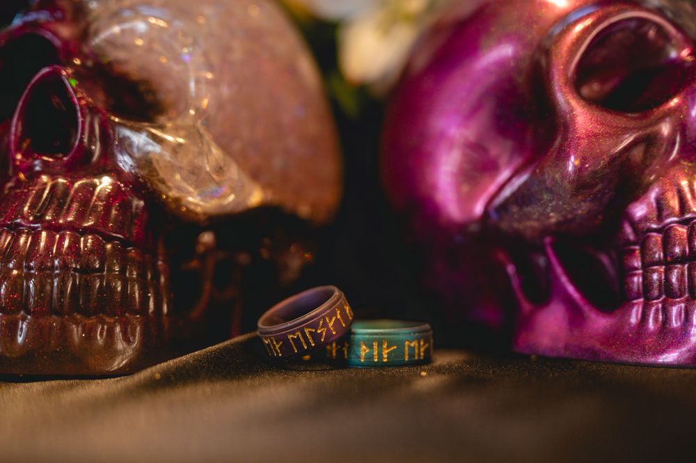 Decorative pink and turquoise skulls arranged in a dark moody setting with dramatic lighting effects.