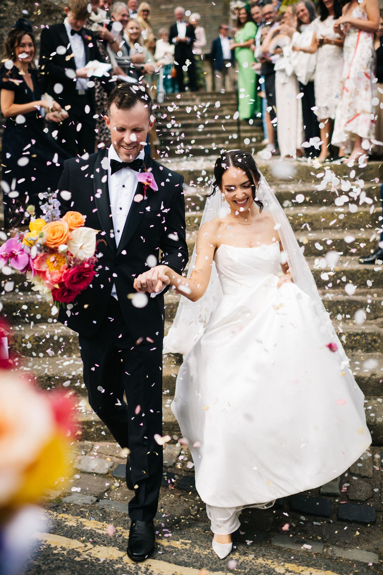 A bride in an elegant white off-shoulder wedding gown with a sweetheart neckline poses with her bouquet. Editorial wedding photographer.