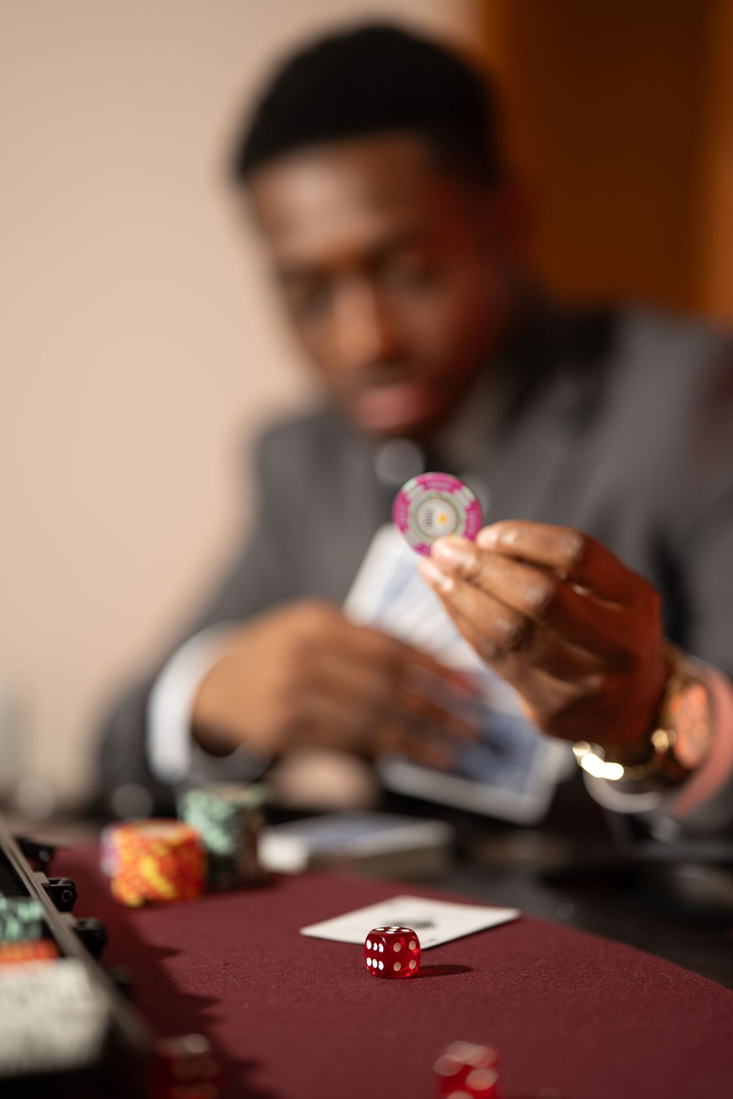 People playing board games on a burgundy table with dice and cards visible in the foreground.