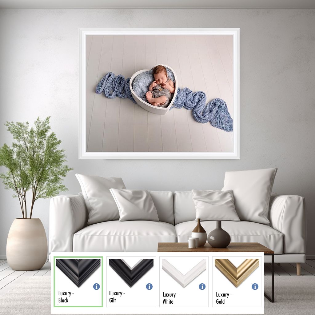 Living room interior mockup with white couch, plant and framed newborn photography art on gray wall.