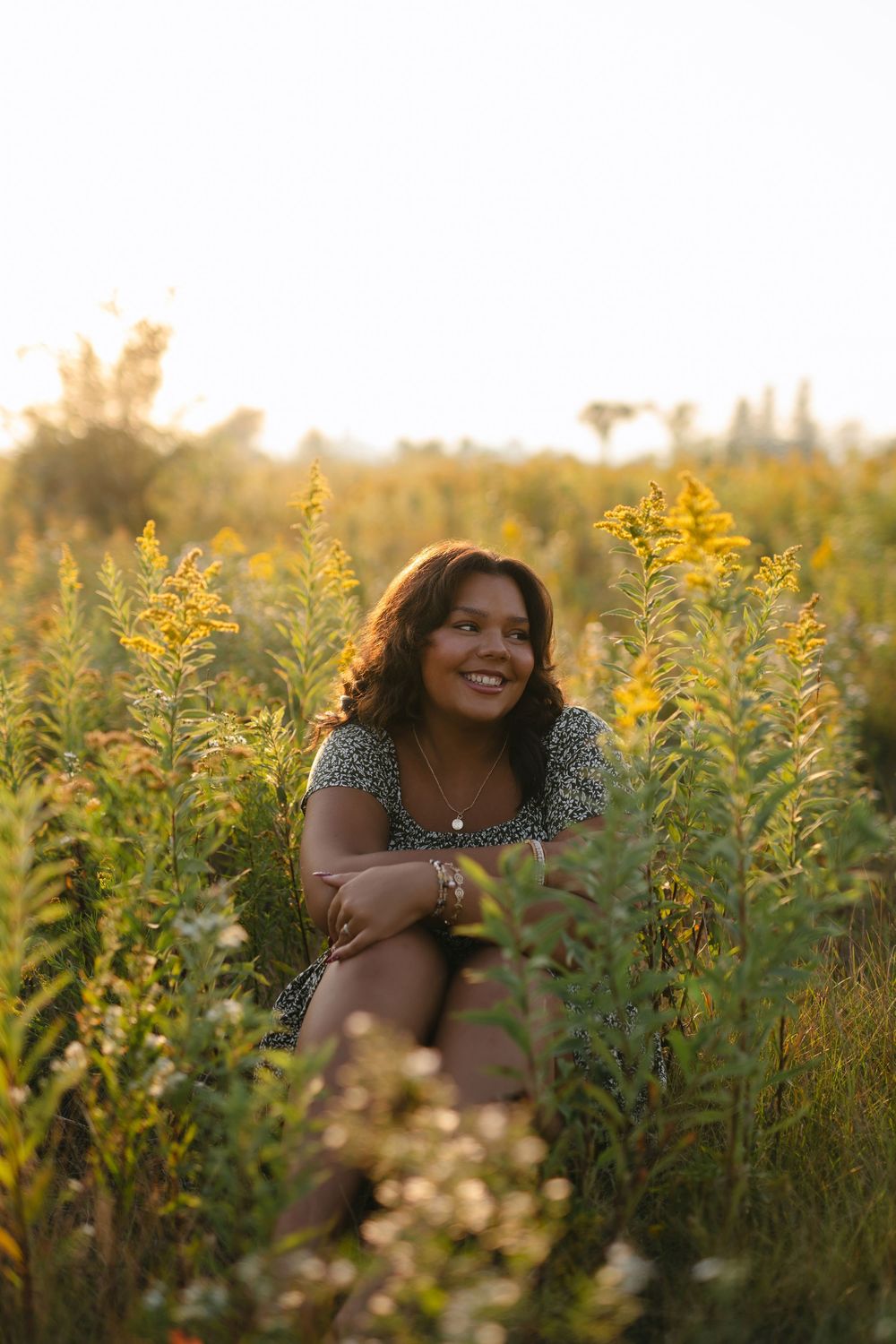 A joyful photoshoot in a field of golden wildflowers during sunset with warm glowing light.