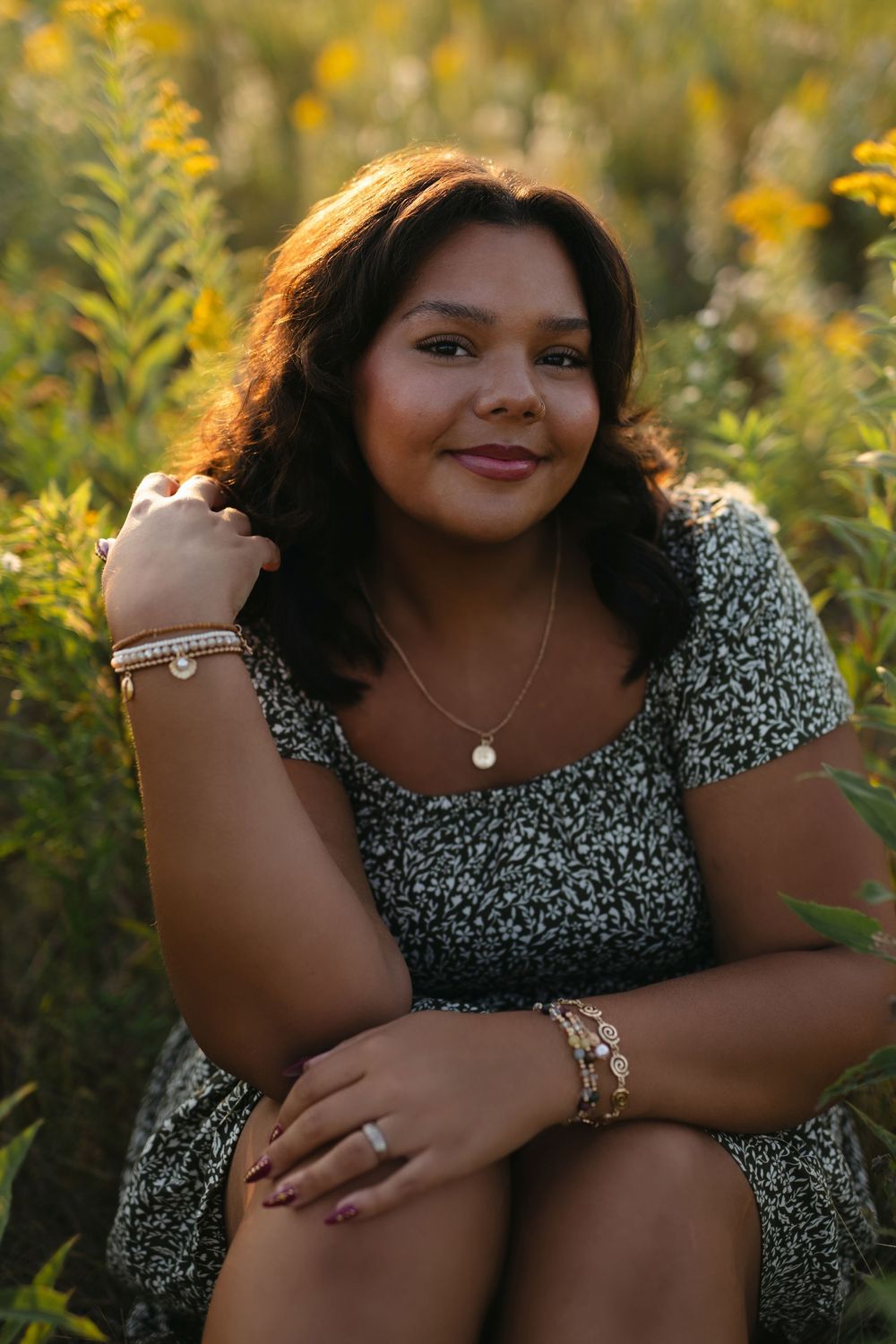 Outdoor portrait session in a field of yellow wildflowers wearing a floral print dress.