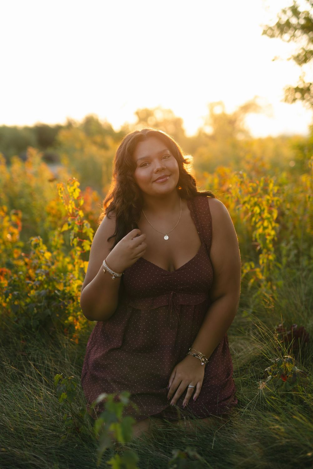 Candid outdoor portrait in a wildflower field at golden hour with warm sunlight filtering through yellow blooms.