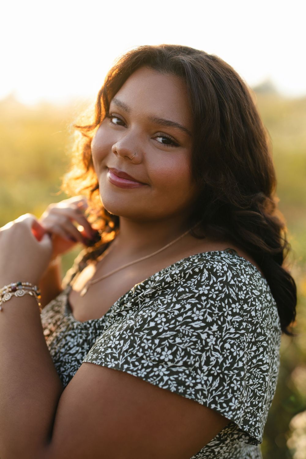 Portrait of someone in a black and white patterned top posing against golden sunset light.