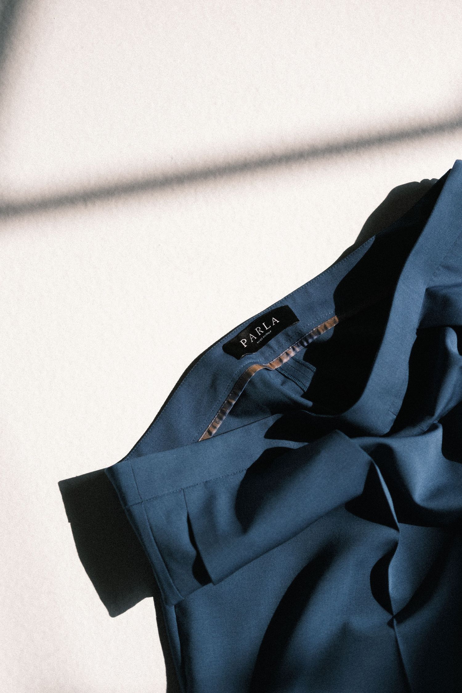 Close-up detail of a navy blue structured blazer showing lapel and collar construction against white background.