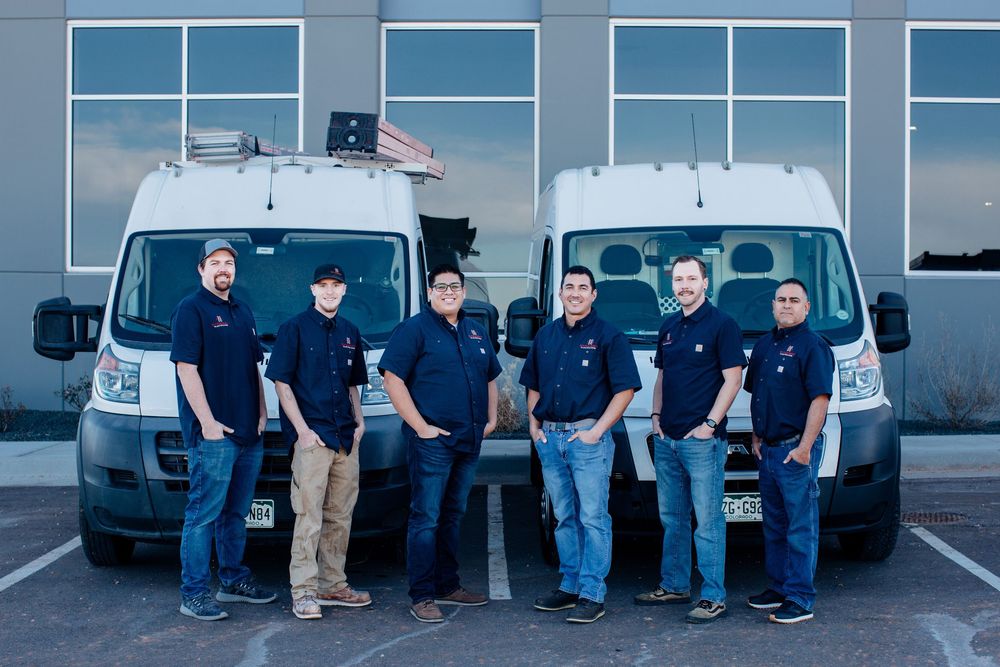 Service team members lined up with company vans in commercial parking lot.