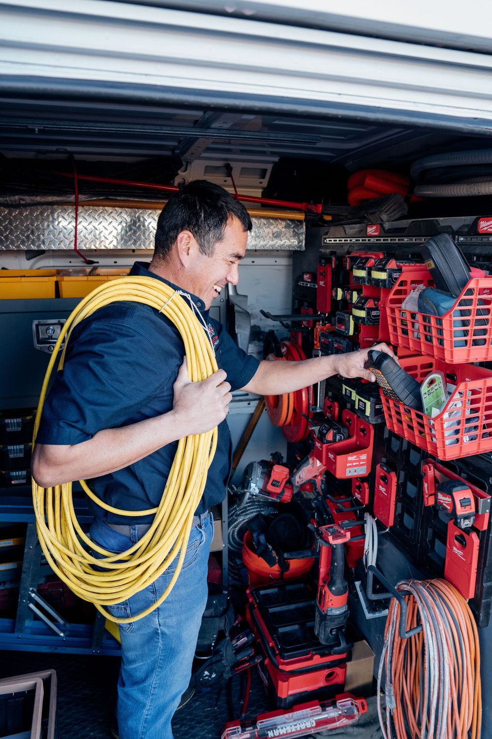 Worker organizing electrical equipment and yellow cables in a storage area.