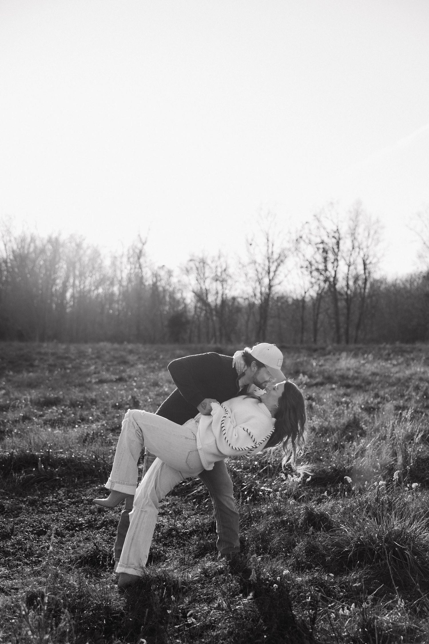 A romantic black and white photo of a couple sharing an intimate moment in a natural outdoor setting.
