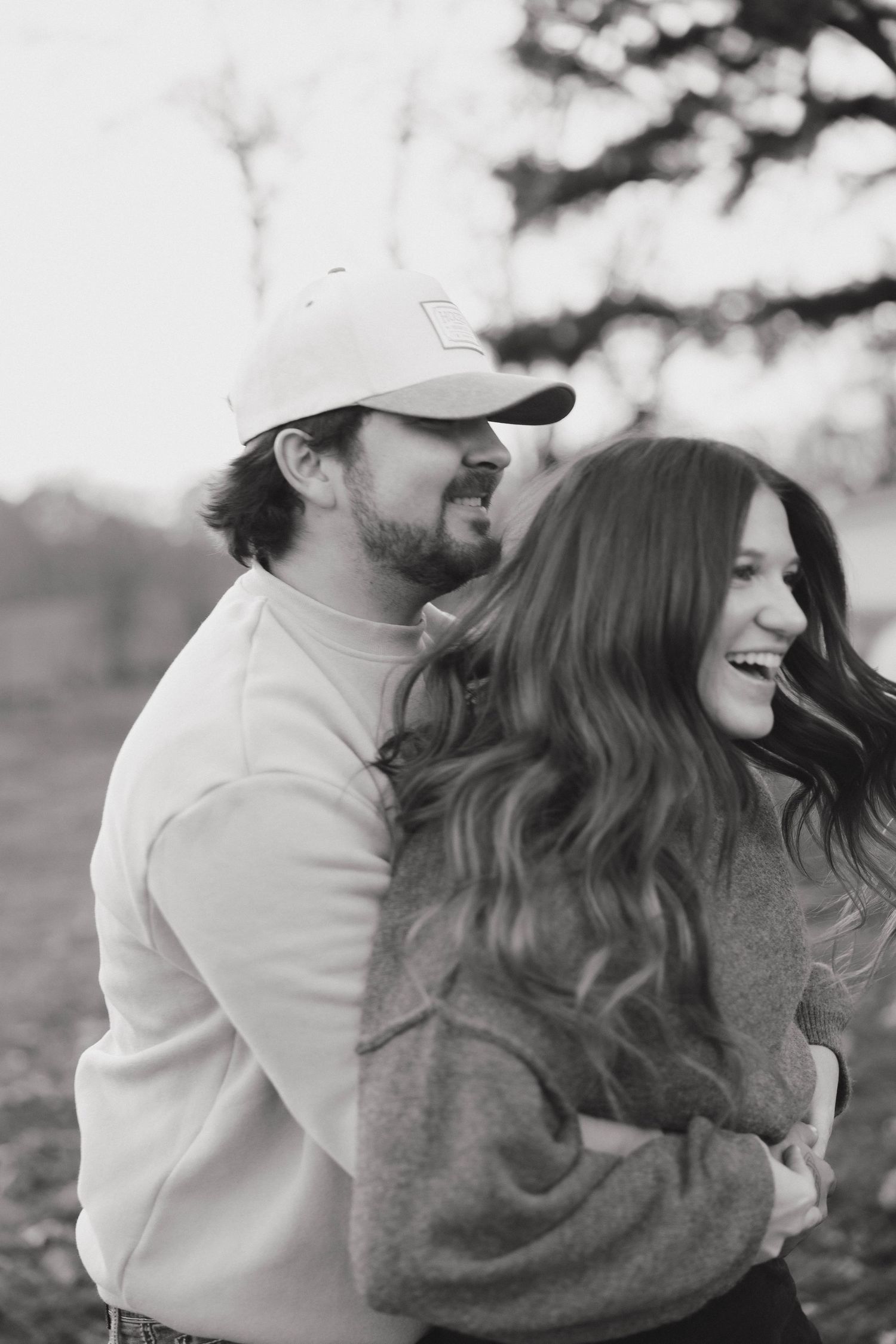 A romantic black and white portrait of a couple sharing a joyful moment outdoors.