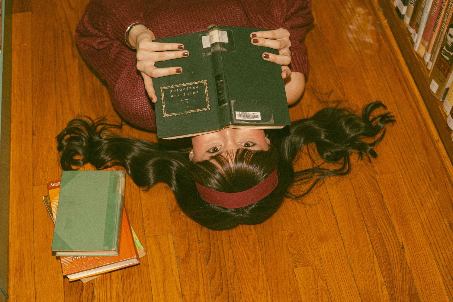 Two students lie on grass reading books together on a sunny autumn day.