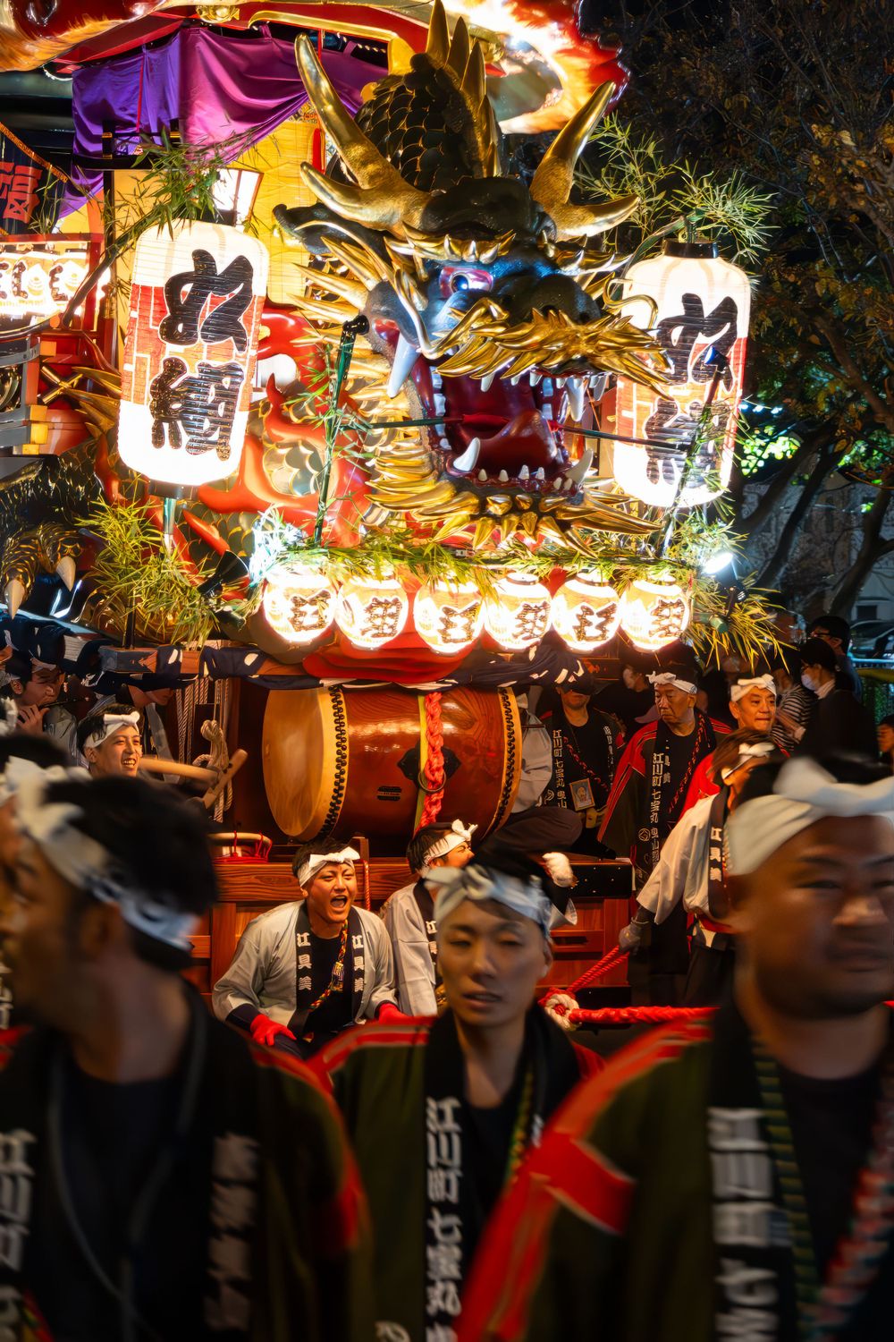 Colorful Japanese festival float with lanterns and dragon decorations during night parade.