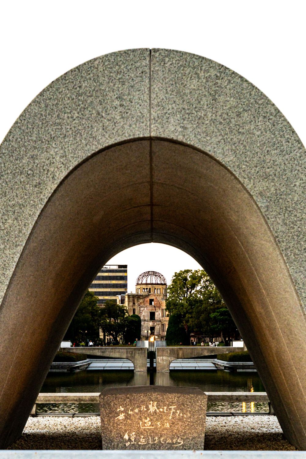 Monument arch frame looking towards the Hiroshima Peace Memorial dome against a cloudy sky.