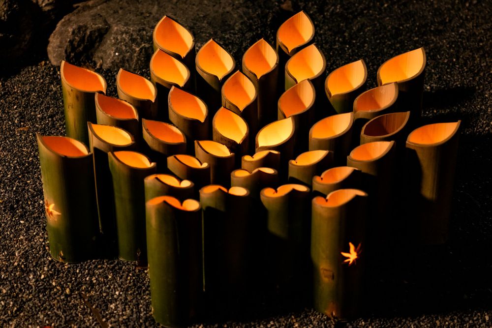 Artistic bamboo lanterns with orange glowing tips arranged in a circular pattern at night.