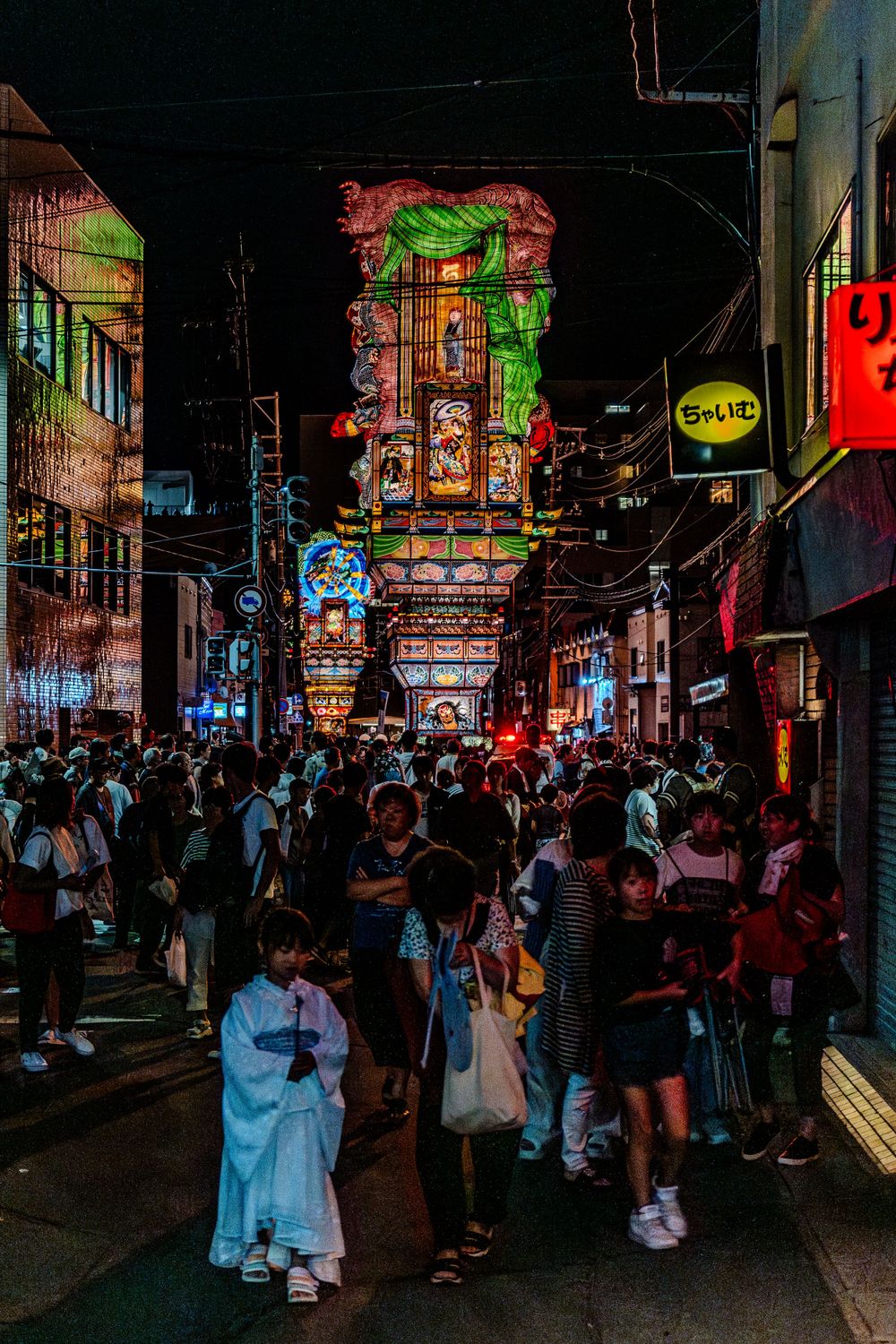 Crowded night street in Japan illuminated by colorful neon signs and advertisements.