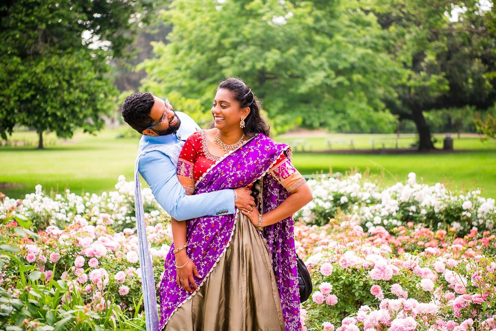 A joyful moment captured in a garden surrounded by pink flowers and greenery.