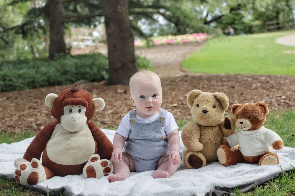 Baby boy with his three teddy bears in the park