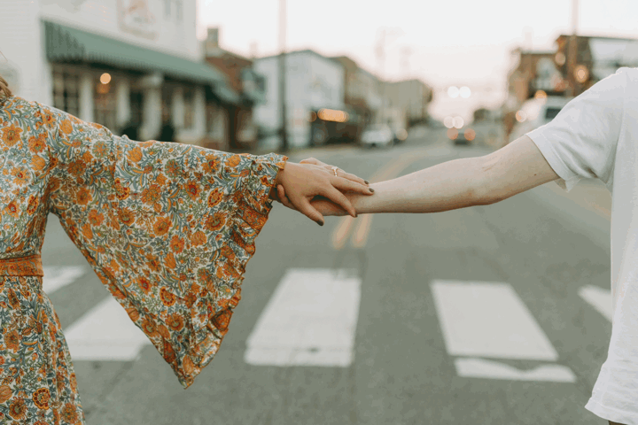 Close-up of hands reaching for each other while crossing a city crosswalk. Floyd, VA