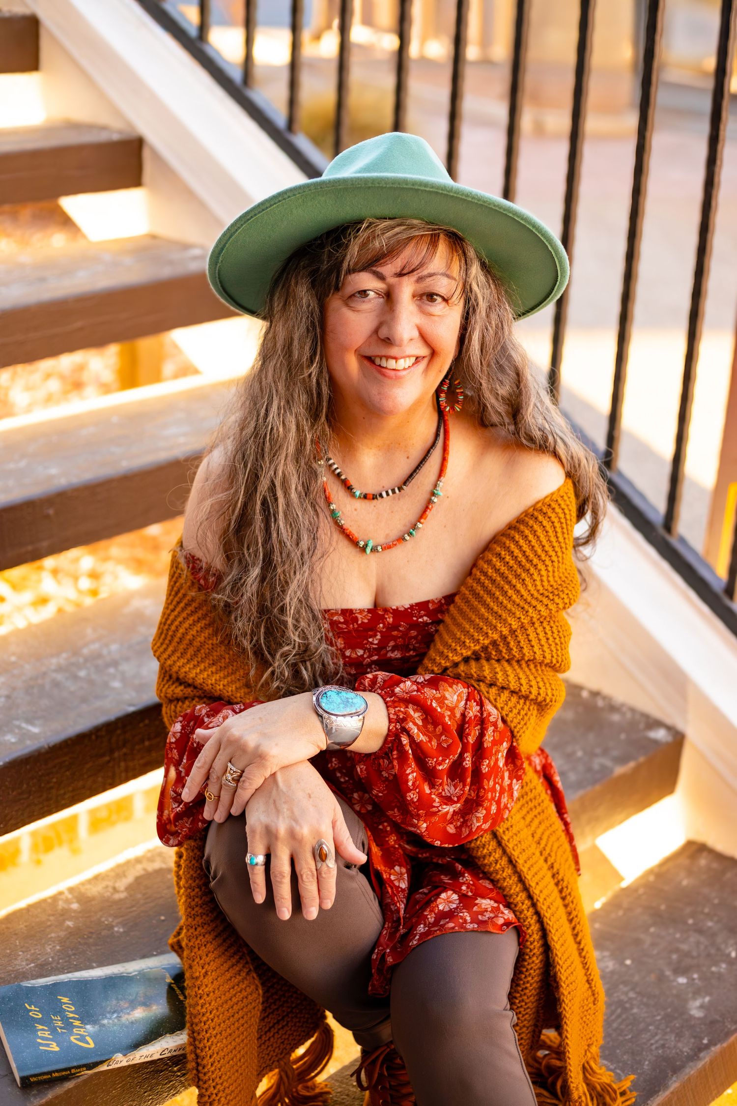 Someone in autumn attire sits casually on wooden steps with warm lighting and rustic decor.
