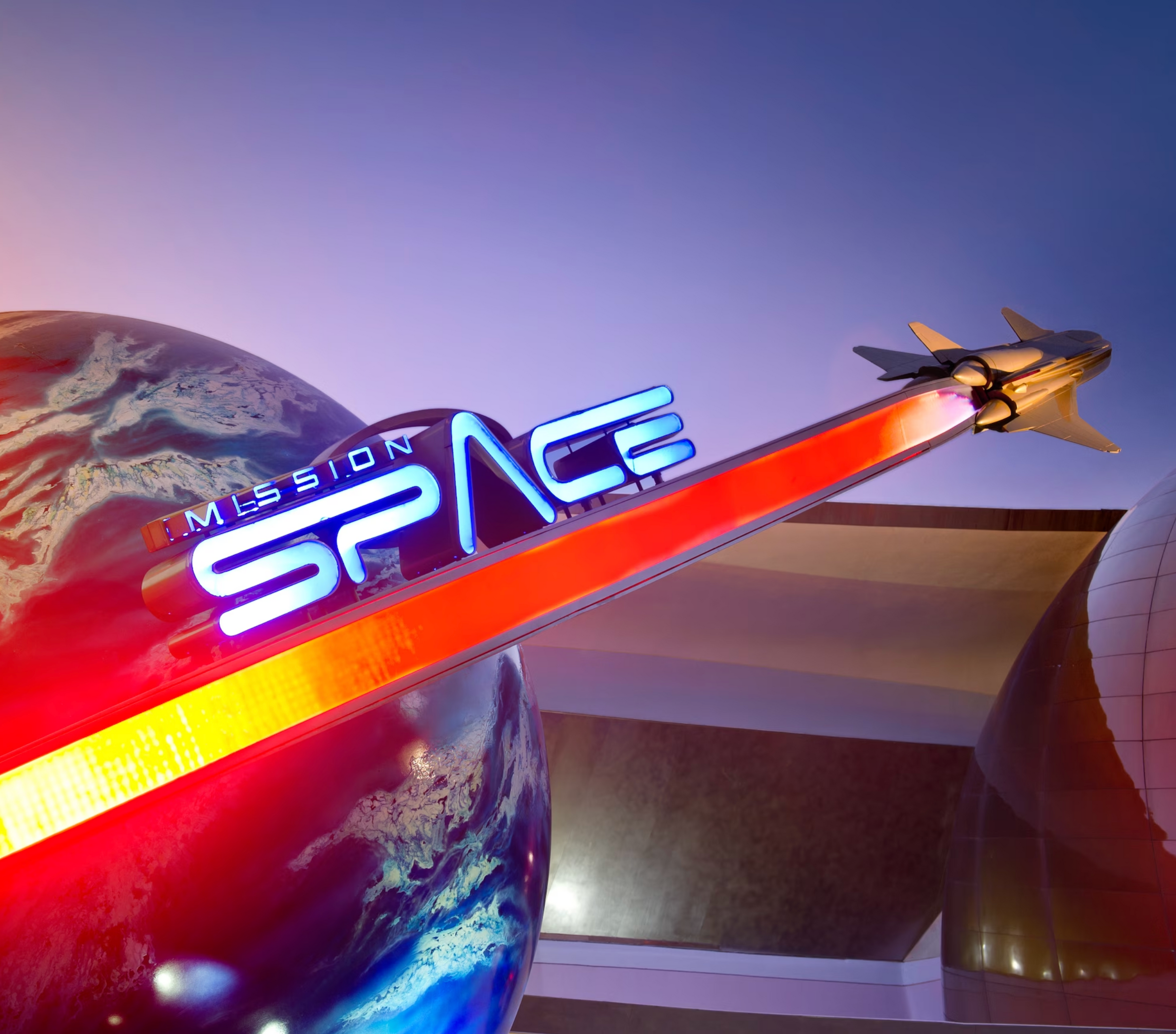 Mission: SPACE attraction sign illuminated at night with Earth globe display at EPCOT theme park.