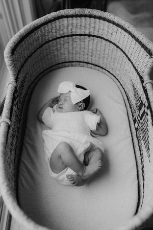 A series of black and white photographs show a sleeping baby nestled in a round basket at different angles.