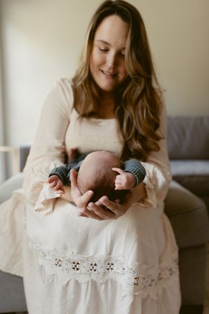 A series of tender moments showing a parent cradling a newborn baby while sitting on a couch in soft natural light.