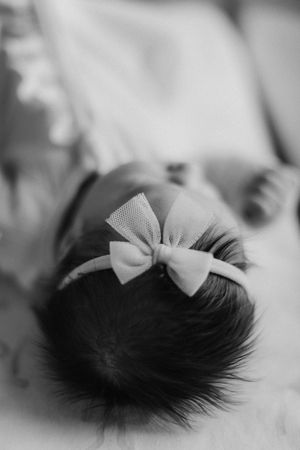 A delicate white tulle bow adorns dark hair in soft black and white photography.