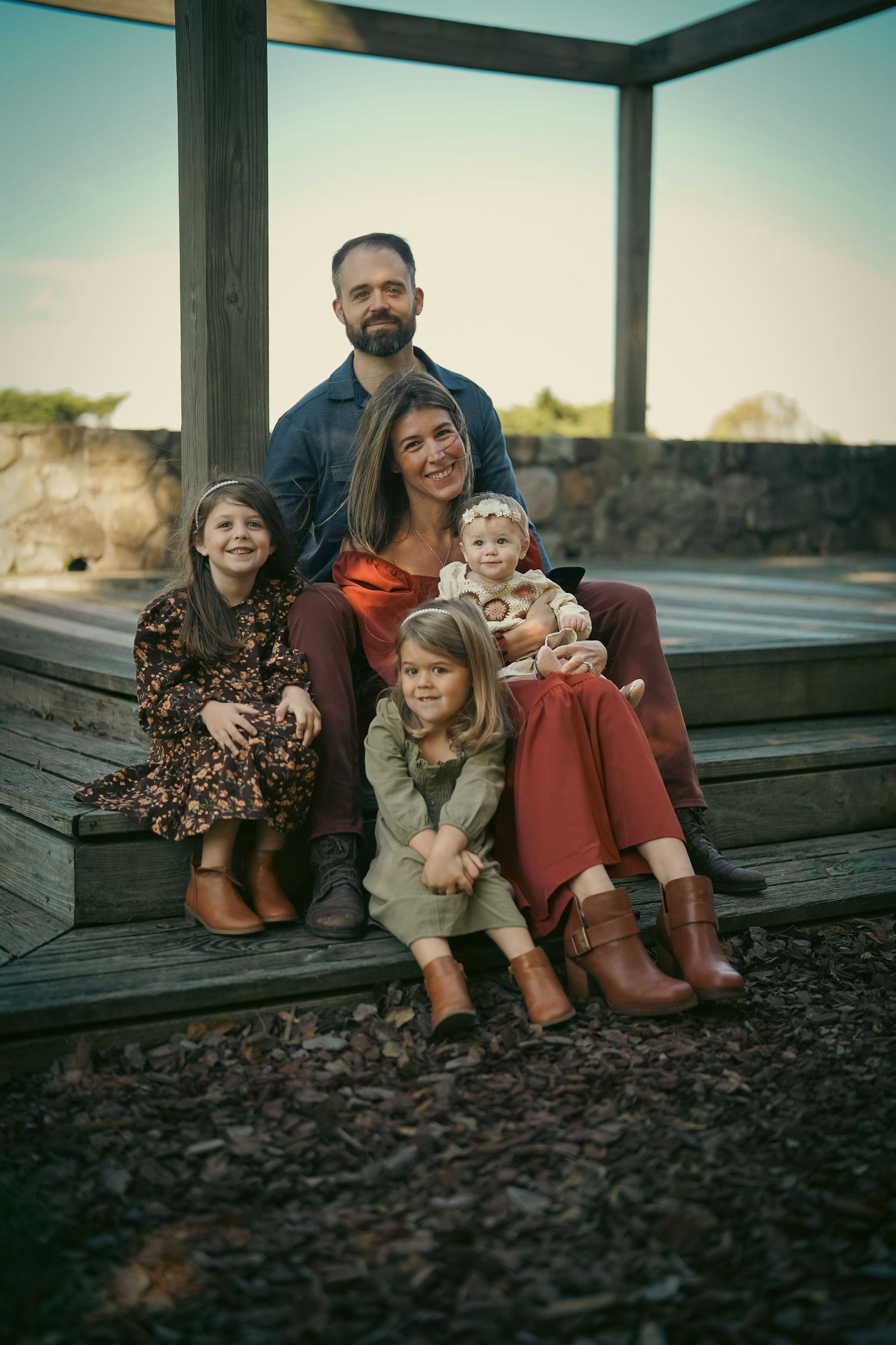 Family sitting together on wooden deck at sunset.