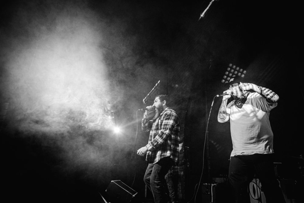 Musicians silhouetted against bright stage lights during dramatic live performance.