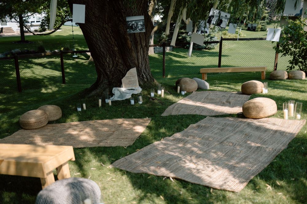 Stone seating and concrete slabs create an outdoor gathering space beneath shady trees in a peaceful park setting.