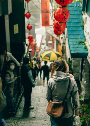 Steep stone steps lead down narrow alley decorated with red Chinese lanterns between traditional buildings.