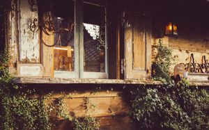 Rustic wooden window frame and facade covered in climbing vines with vintage aesthetic.