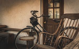 Vintage bicycle parked against weathered wall with rocking chair in warm evening light.