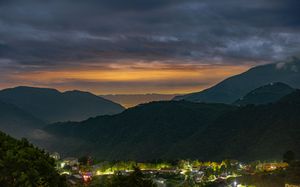 Night panorama of mountain valley with small town lights glowing in the darkness.
