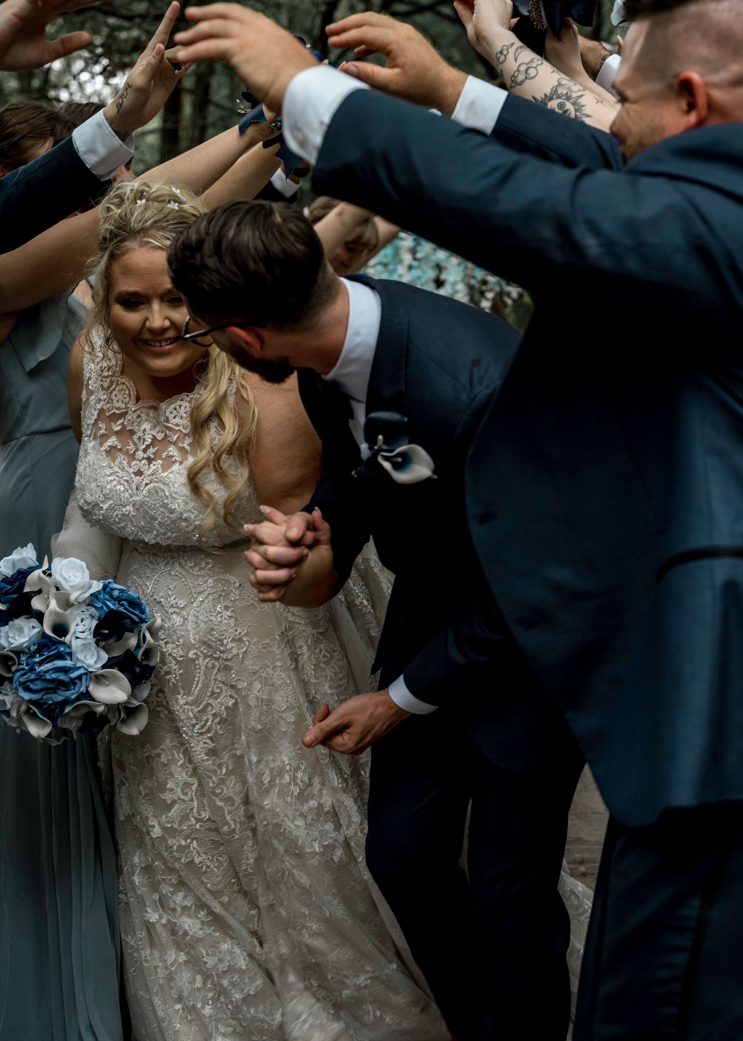 A joyful celebration at an outdoor wedding with bridesmaids in blue dresses and groomsmen in navy suits.