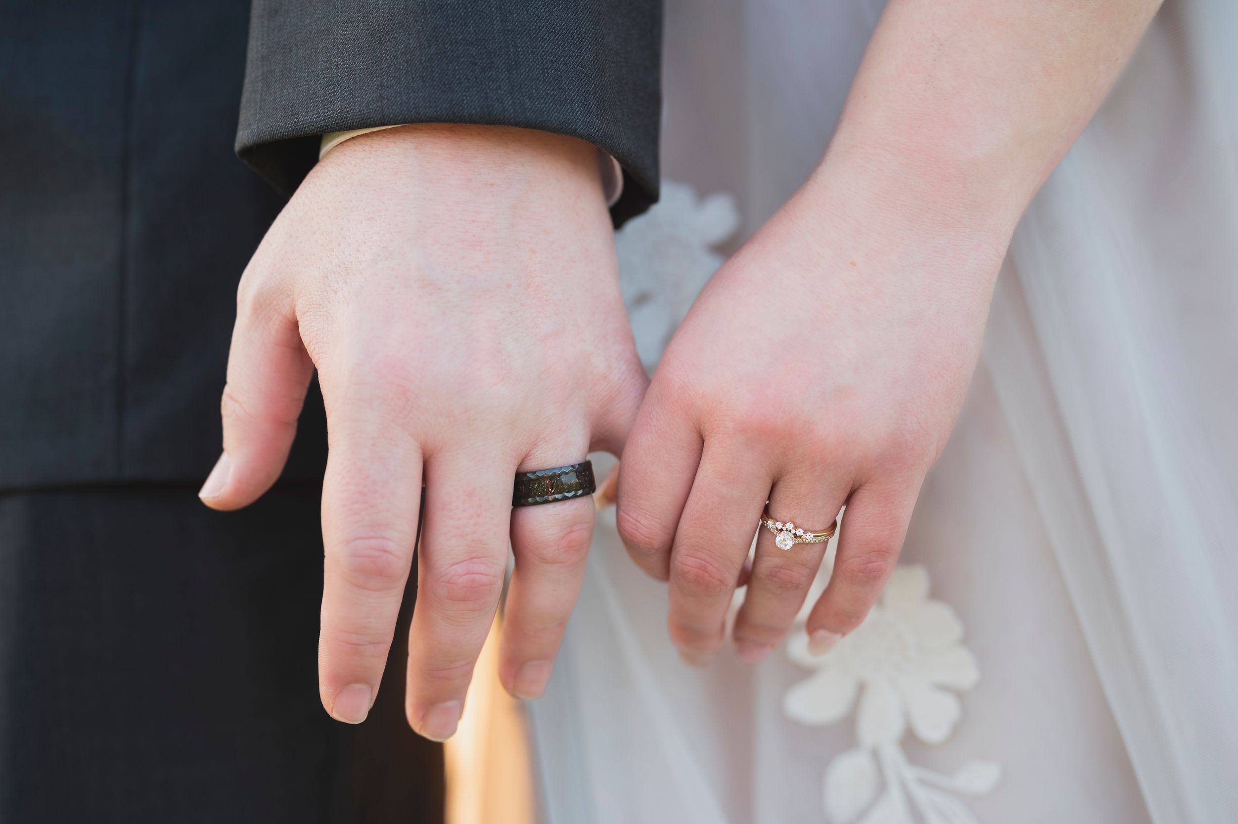 Several hands hold white candles in sequence while lighting them from one to another in a darkened setting.