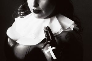 A "nun" in latex holds a communion wafer.