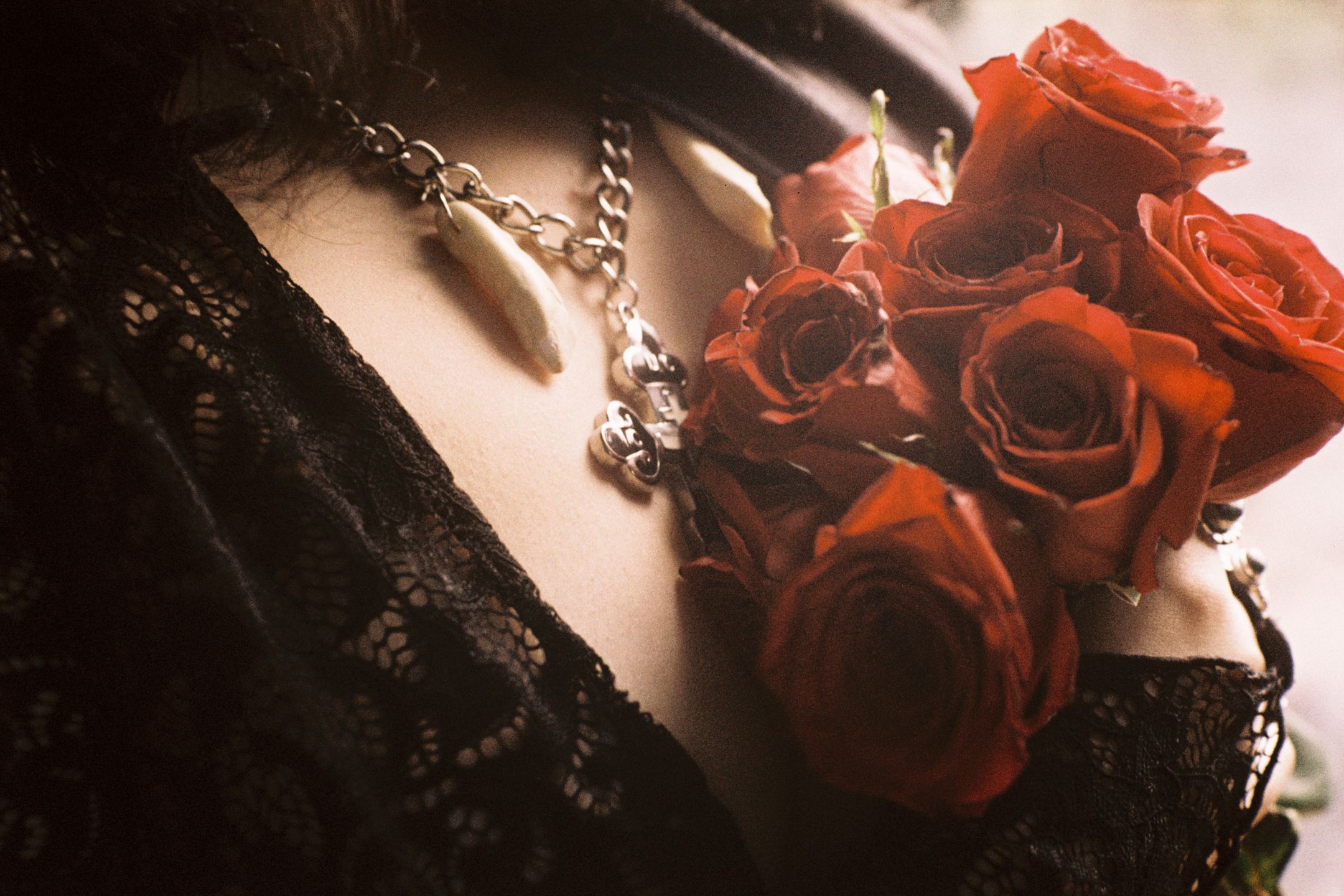 A femme holds red roses against their chest.
