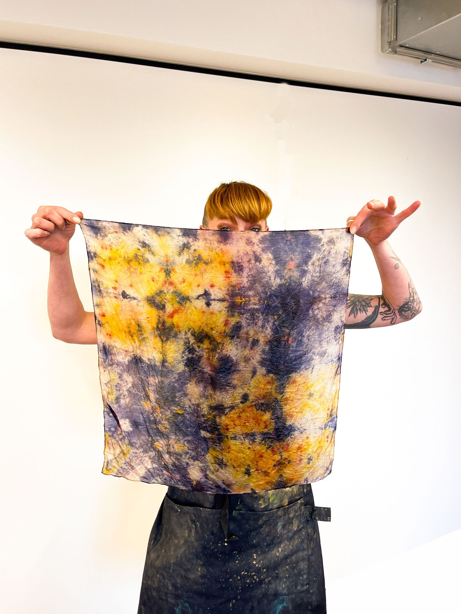 a woman holding a naturally dyed silk scarf in a room