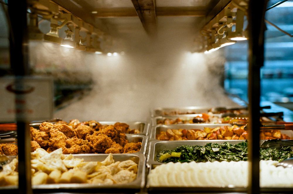 Steam rising from hot food display case showing various prepared dishes.