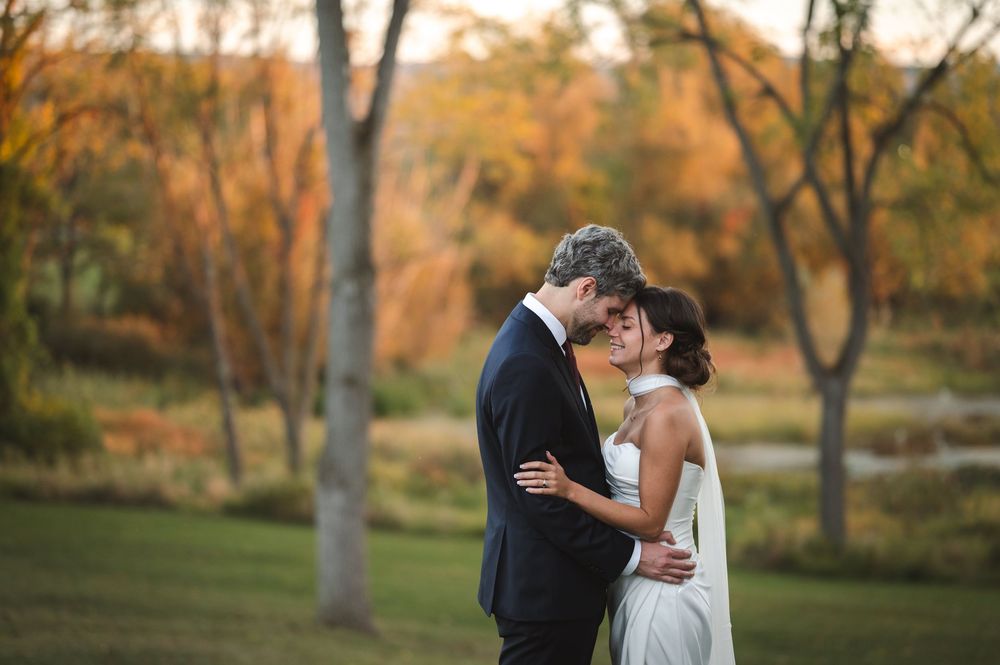 Romantic couple embraces in a golden autumn park setting during sunset with warm fall foliage in background at Drowned Lands Brewery Warwick